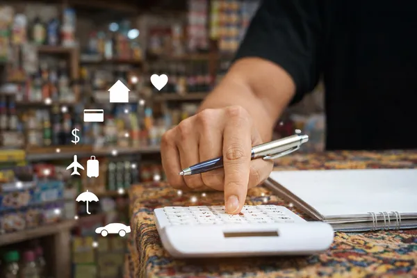 Persona usando una calculadora y anotando gastos para organizar su presupuesto.